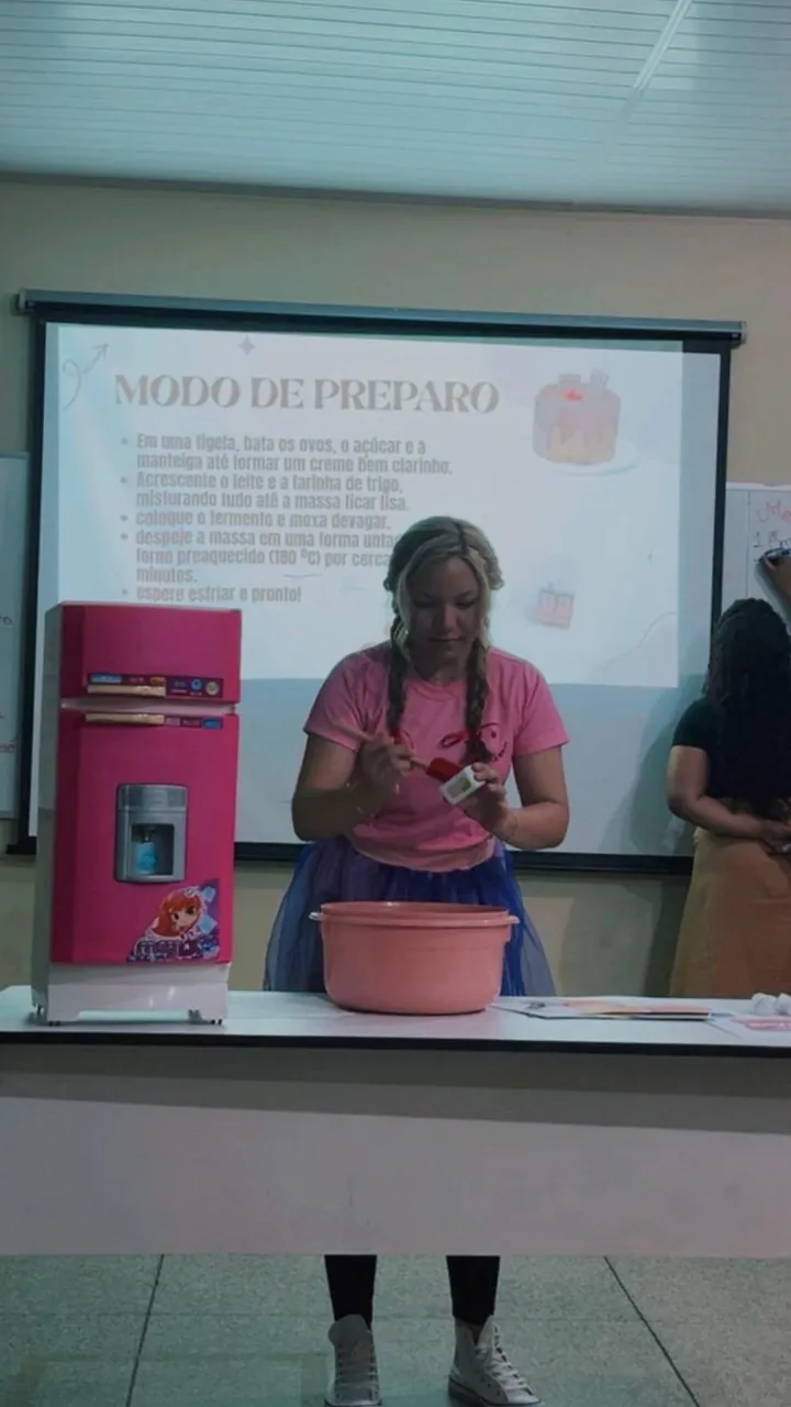 Lanna Campos durante a apresentação sobre modo de preparo, com uma panela rosa sobre a mesa.