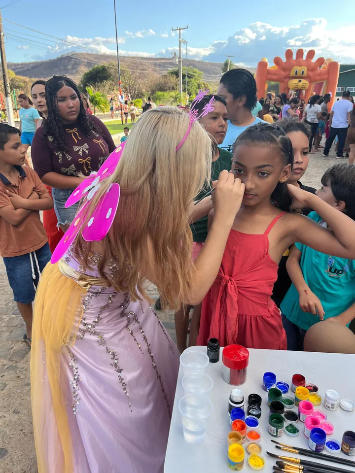 Lanna Campos fantasiada de fada, pintando o rosto de uma menina em uma festa de rua.